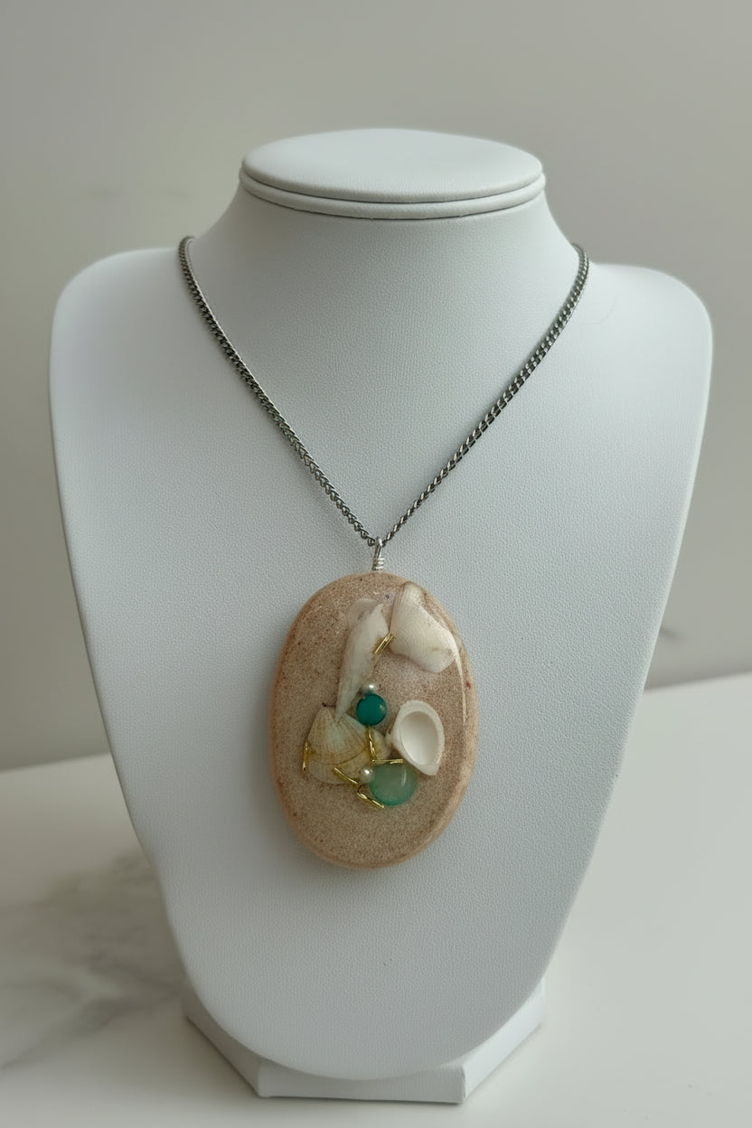 Necklace with a pendant featuring shells and beads on a mannequin.