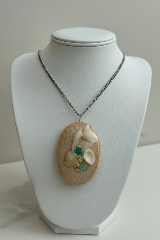 Necklace with a pendant featuring shells and beads on a mannequin.